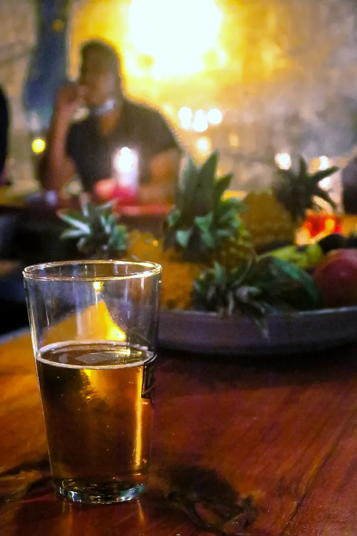 A pint of draught on the bar, candles and pineapples glowing behind