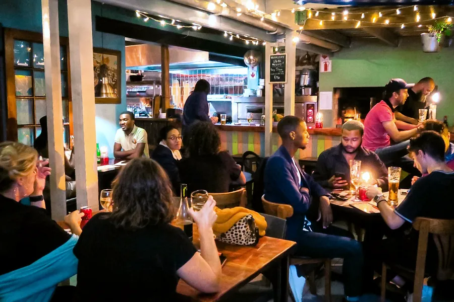 A full room of friends at candle-lit tables with the bar behind